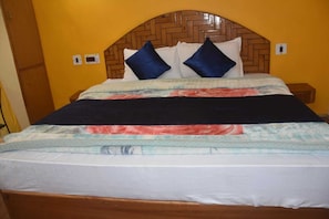 A bed with a wooden headboard, multiple pillows, and a patterned bedspread. - Hotel Sidhartha  (Manali)