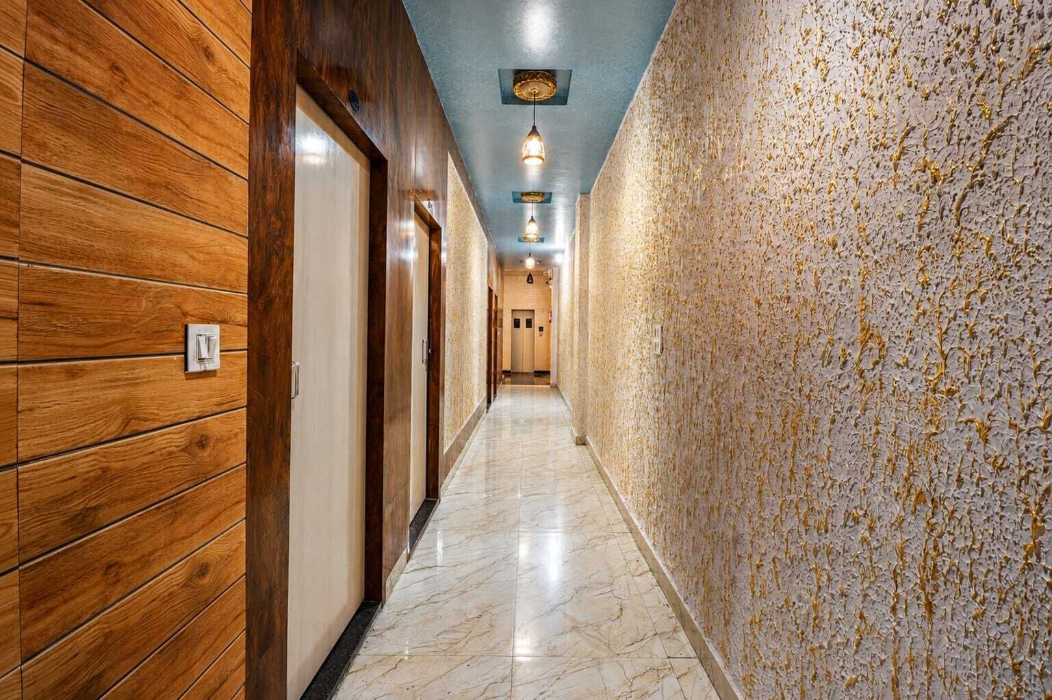 A hallway with wooden paneling on one side and a textured wall on the other, leading to a door at the end.