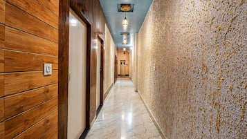 A hallway with wooden paneling on one side and a textured wall on the other, leading to a door at the end.