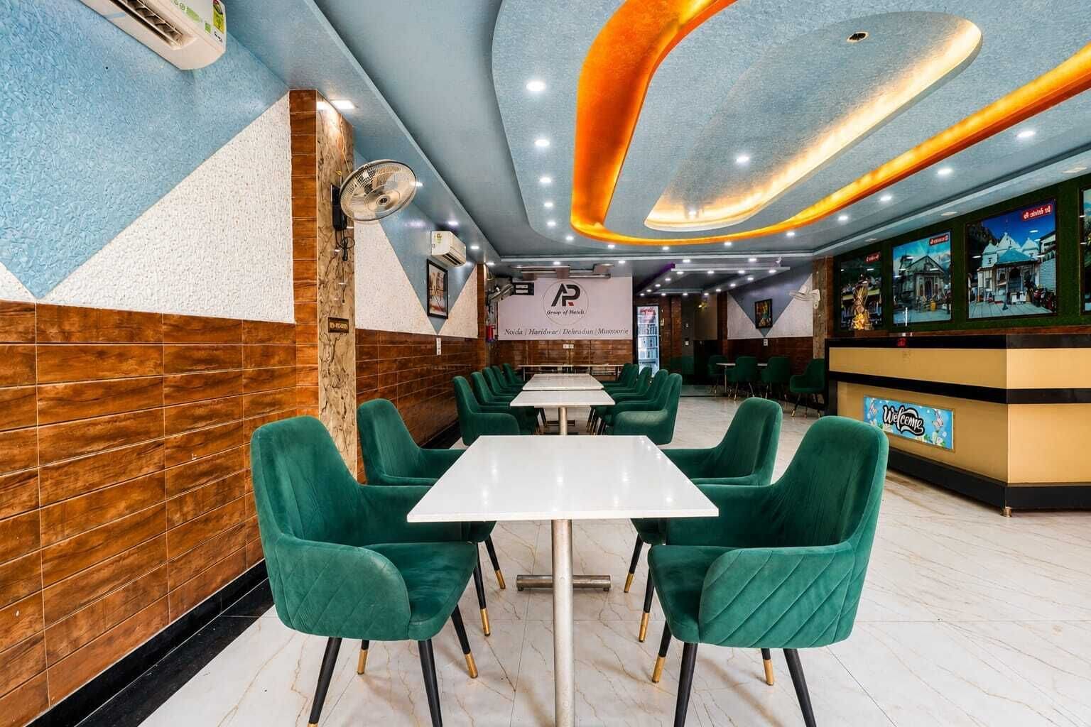 A restaurant interior with green upholstered chairs, white tables, and a modern ceiling design.