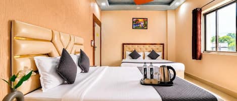 A hotel room with a bed, a bedside table, a nightstand, a window with curtains, a ceiling fan, and a painting on the wall.