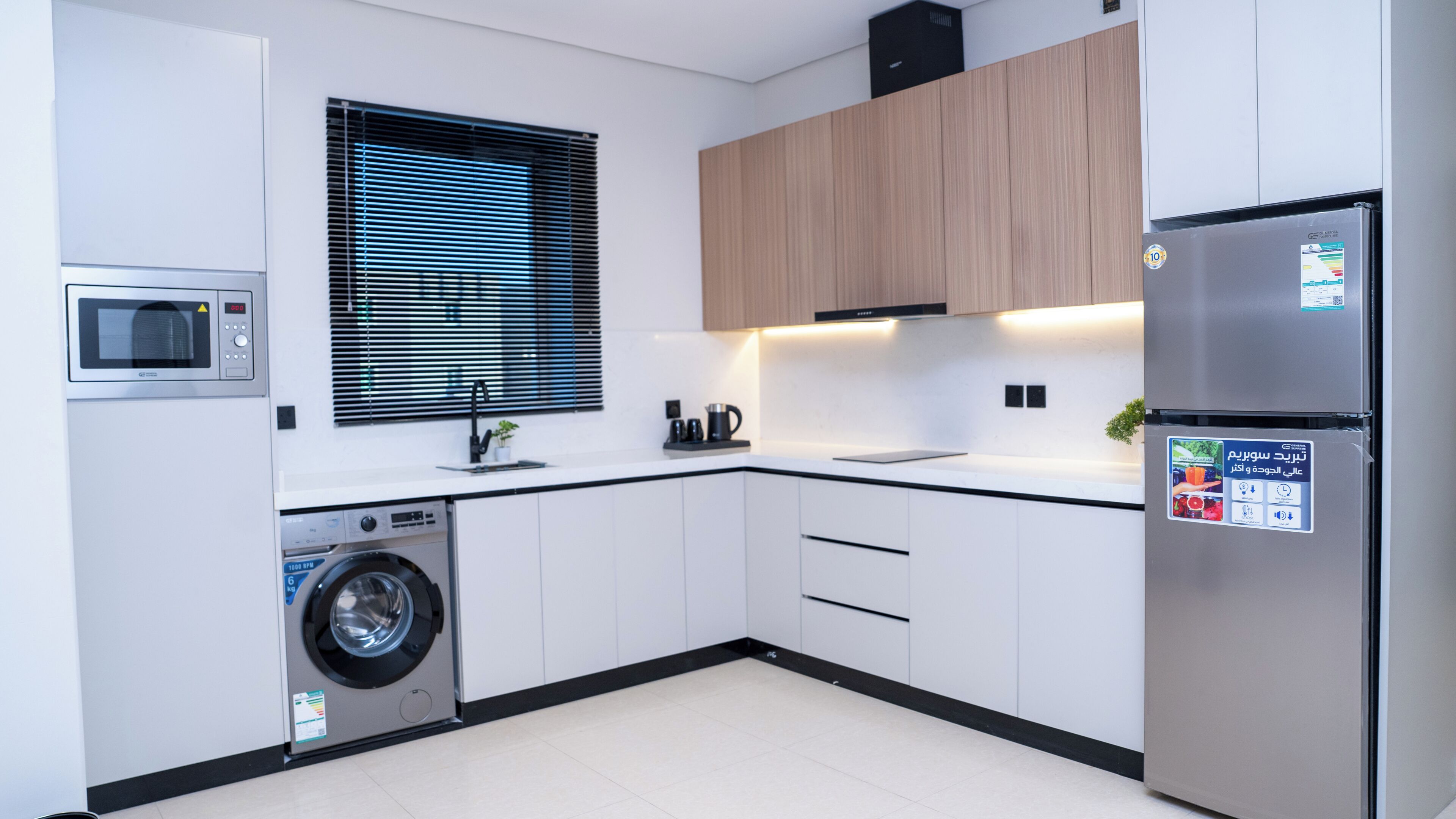 A modern kitchen with a built-in washing machine, a microwave, and a refrigerator.