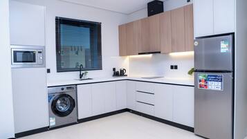 A modern kitchen with a built-in washing machine, a microwave, and a refrigerator.