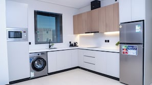 A modern kitchen with a built-in washing machine, a microwave, and a refrigerator. - Darina Serviced Apartments2 (Riyadh)