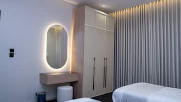 A hotel room with a bed, a bedside table, a mirror, a wardrobe, and a curtain.