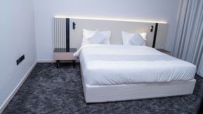 A hotel room with a large bed, bedside tables, a nightstand, and a wall-mounted light fixture. - Darina Serviced Apartments2 (Riyadh)