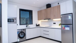 A modern kitchen with a washing machine, microwave, and refrigerator. - Darina Serviced Apartments2 (Riyadh)