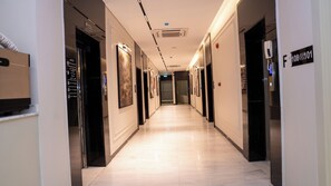 A hotel corridor with a marble floor, framed artwork on the walls, and an elevator on the right. - Darina Serviced Apartments2 (Riyadh)