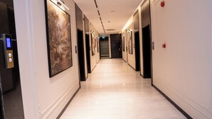 A hotel corridor with a marble floor, framed artwork on the walls, and a digital elevator control panel. - Darina Serviced Apartments2 (Riyadh)