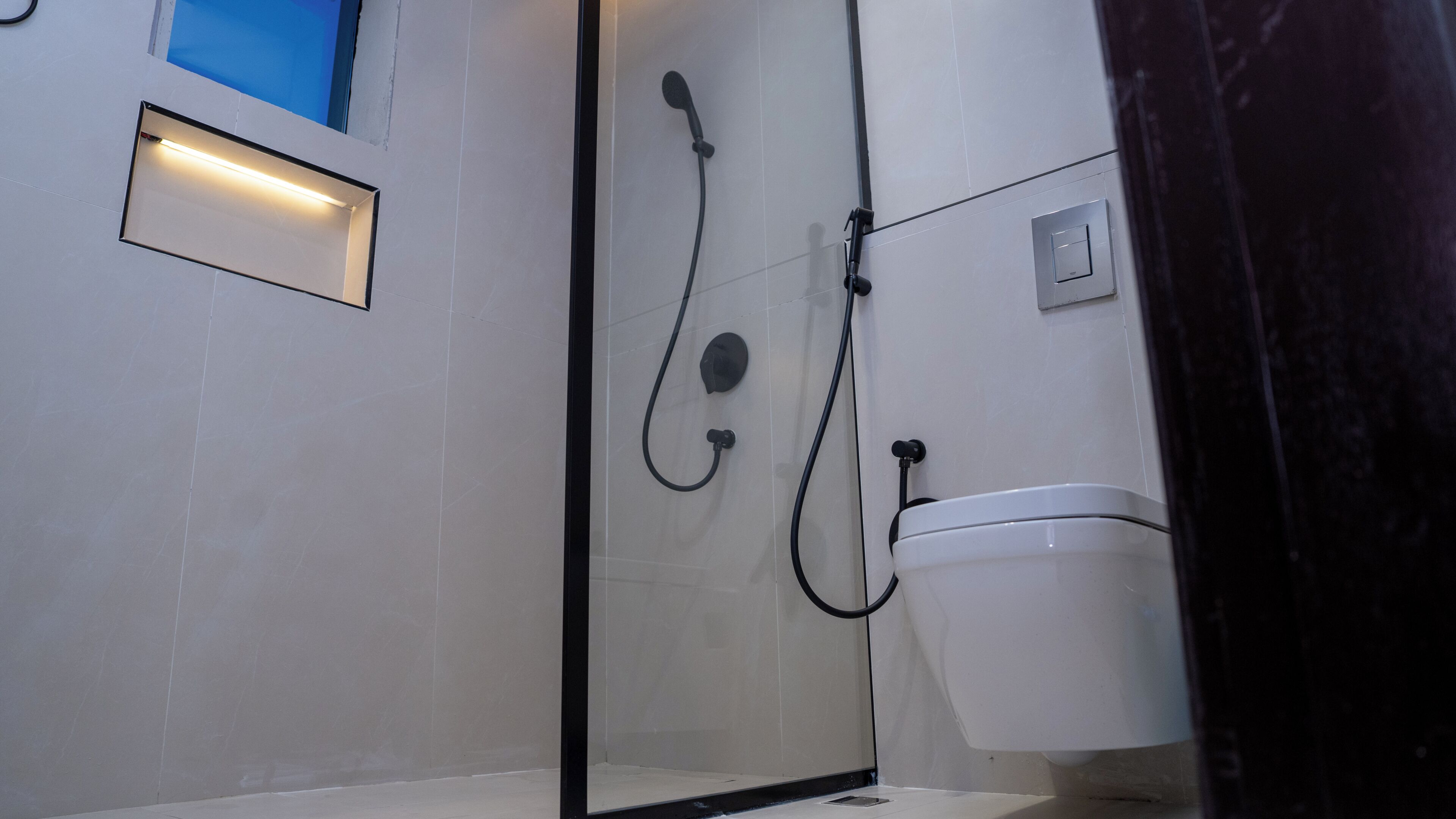 Un baño moderno con cabina de ducha de vidrio, inodoro y aplique de pared.
