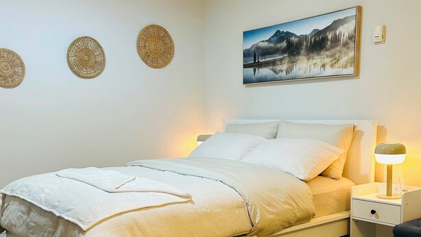 Une chambre à coucher avec un lit, une table de chevet, une lampe et un tableau accroché au mur.