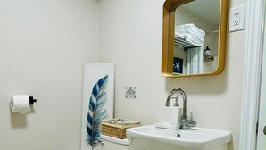 Une petite salle de bain propre, équipée de toilettes, d’un lavabo et d’un miroir.