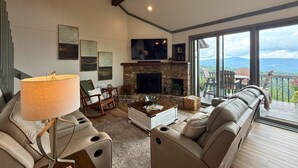 Un amplio salón con chimenea, un sofá, una mesa de centro y una televisión.