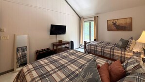 Un dormitorio con dos camas, televisión, ventana con cortinas y un cuadro en la pared.