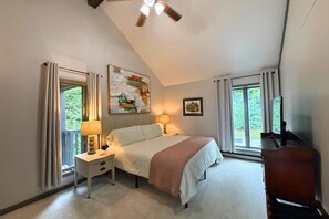 Une chambre à coucher avec un lit, des lampes de chevet, un ventilateur de plafond et une fenêtre avec des rideaux.