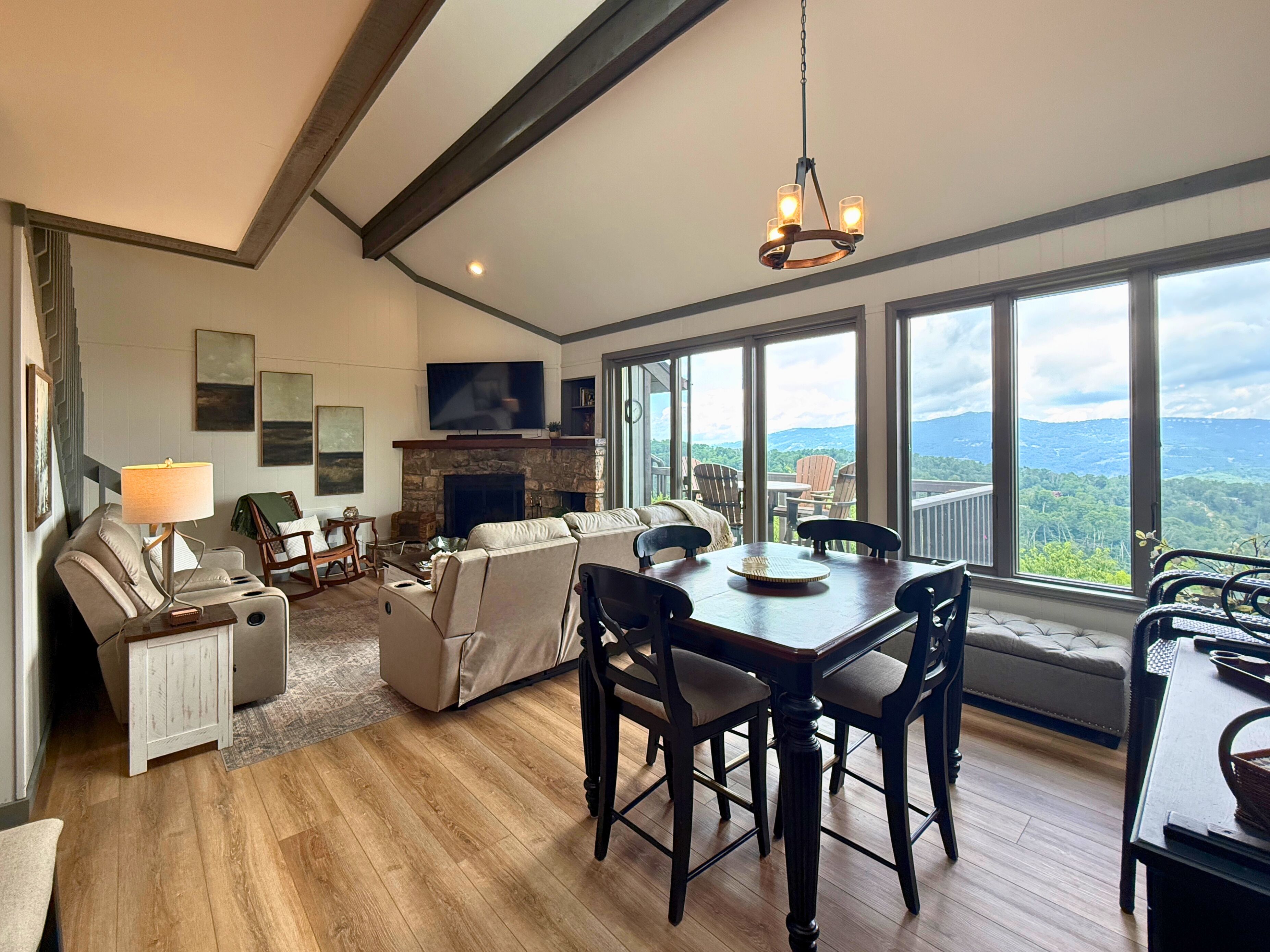 A spacious living room with a fireplace, a dining area, and large windows offering a mountain view.