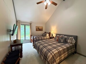 Une chambre avec deux lits, un ventilateur de plafond, une télévision et une fenêtre avec des rideaux.