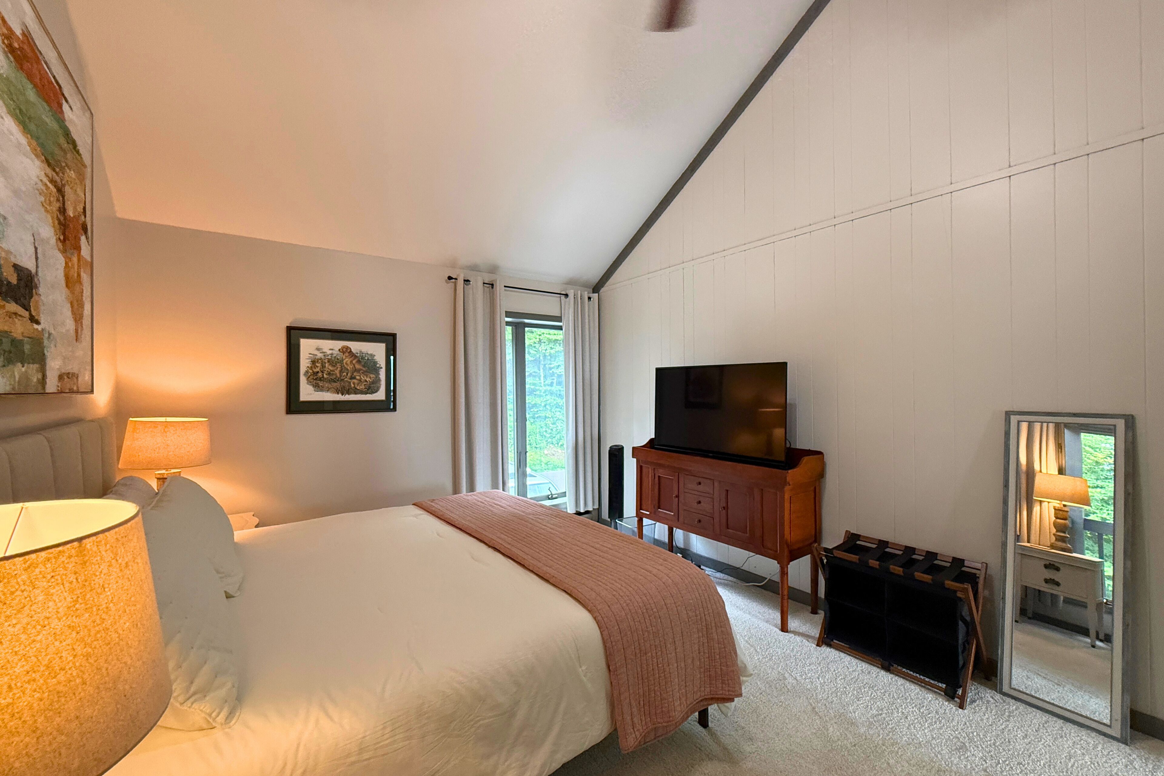 Una habitación de hotel con cama, televisor, escritorio y espejo.