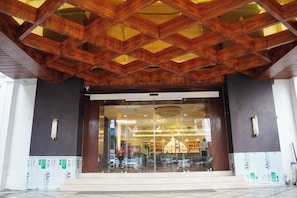 Entrada de un edificio con estructura de techo de madera y puertas de cristal.