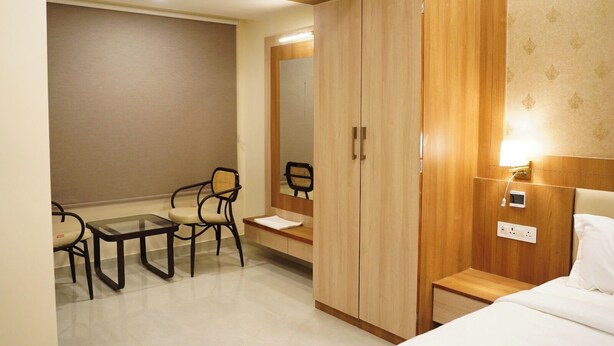 Ein Hotelzimmer mit einem Bett, einem Schreibtisch mit Stuhl, einem Kleiderschrank und einem Nachttisch mit Lampe.