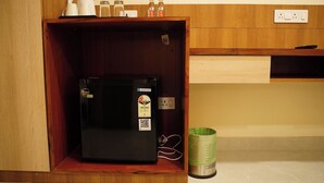 Eine kompakte Küche mit einem eingebauten schwarzen Kühlschrank, einer Kaffeemaschine und einem Wasserspender auf der Arbeitsplatte.