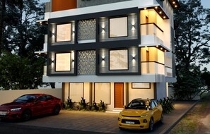 A modern multi-story building with large windows and a carport. - Lovely 2-bedroom apartment with AC for a relaxing stay (Ernakulam)