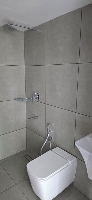 Ein modernes Badezimmer mit Dusche, einer Glasablage und einer weißen Toilette.