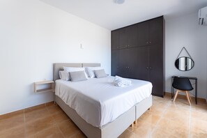 Ein modernes Schlafzimmer mit Bett, Kleiderschrank, kleinem Tisch und Stuhl.