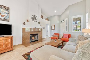 A living room with a fireplace, a television, and a sofa. - Palm Desert Resort Condo | Preston Trail | Near Indian Wells Tennis Garden & Golf (Palm Desert)