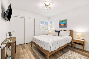 A bedroom with a bed, bedside tables, a TV mounted on the wall, and a ceiling light fixture. - Palm Desert Resort Condo | Preston Trail | Near Indian Wells Tennis Garden & Golf (Palm Desert)