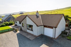 A two-story house with a tiled roof, a garage, and a fenced yard.