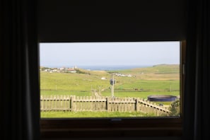 A view through a window of a rural landscape with houses, a fence, and a large water tank.