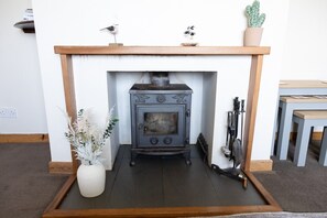A fireplace with a decorative mantel, a potted plant, and a small table to the right.