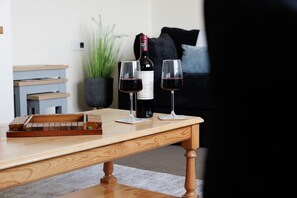 Een houten tafel met een fles wijn en twee glaasjes erop.