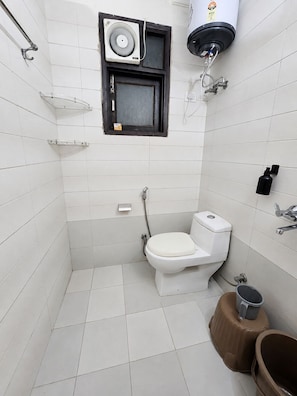 Um banheiro pequeno com azulejos, vaso sanitário, chuveiro, porta-toalhas e aquecedor de água.