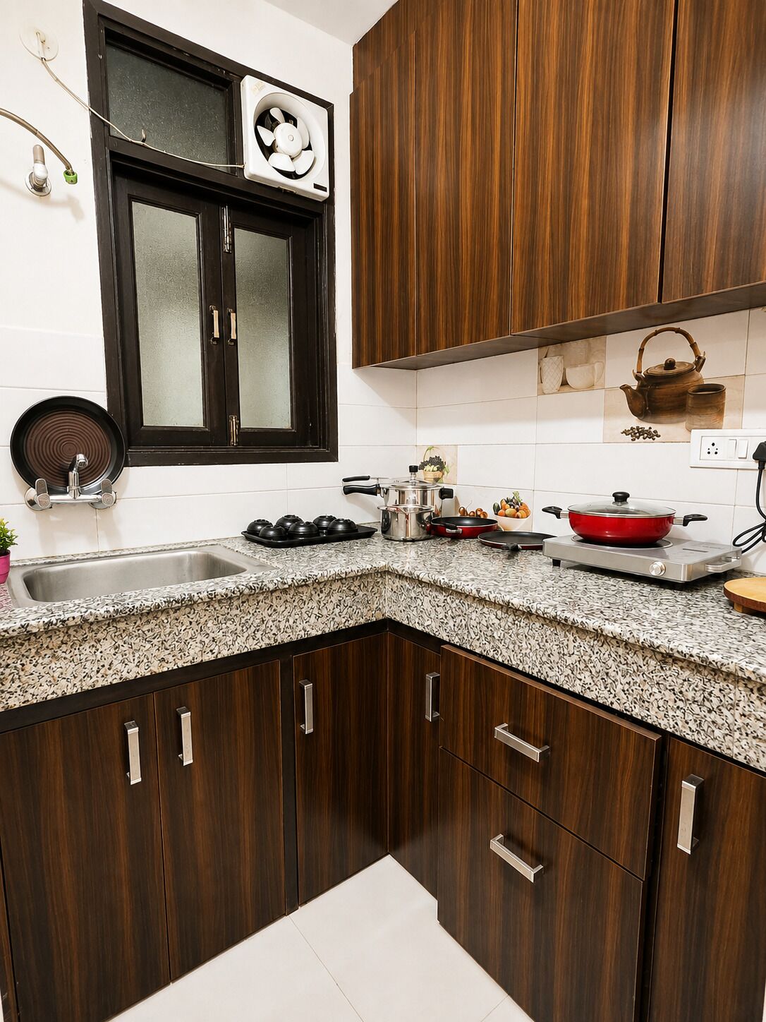 Cozinha com armários de madeira escura, bancada de granito, janela com ventilador e diversos eletrodomésticos.