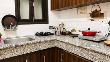Cozinha com armários de madeira escura, bancada de granito, janela com ventilador e diversos eletrodomésticos.