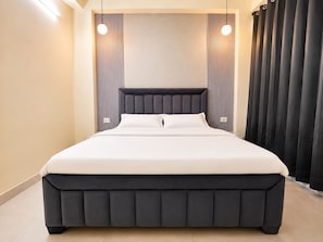 Quarto moderno com uma cama grande, cabeceira e cortina.