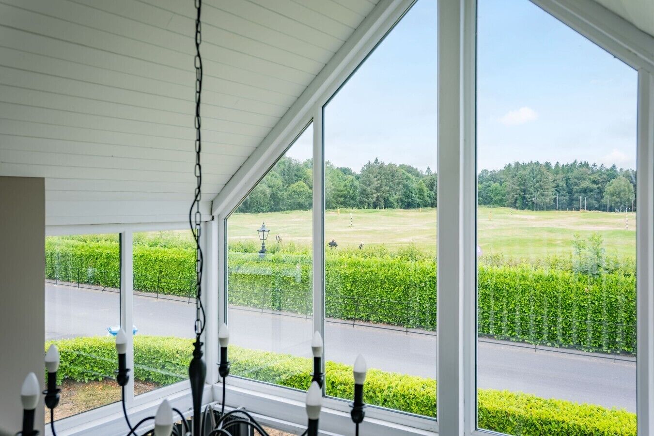 Una habitación con ventanas amplias que dan a un paisaje verde y una carretera.