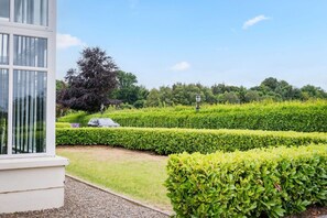 A well-maintained garden with neatly trimmed hedges, a paved pathway, and a parked car. - Hot tub, golf views, sleeps 10 — 400m from Lough Erne (Enniskillen)