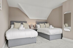 Ein Schlafzimmer mit zwei Betten, Nachttischen, Lampen und einem Spiegel.