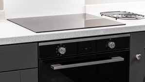 Eine Küche mit einem schwarzen Backofen, einer Edelstahl-Dunstabzugshaube und einer weißen Arbeitsplatte.
