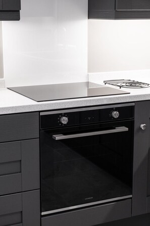 Eine Küche mit einem schwarzen Backofen, einer Edelstahl-Dunstabzugshaube und einer weißen Arbeitsplatte.