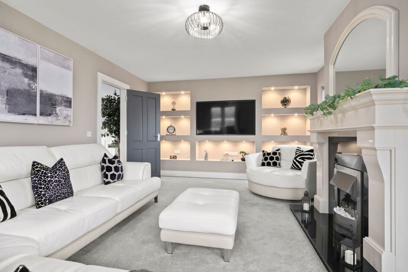 Un salon moderne avec un canapé blanc, un fauteuil blanc, une cheminée et un téléviseur à écran plat fixé au mur.