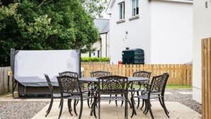 Eine Terrasse im Freien mit Tisch, Stühlen, einem Grill und einem Holzzaun.