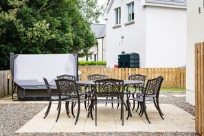 Eine Terrasse im Freien mit Tisch, Stühlen, einem Grill und einem Holzzaun.