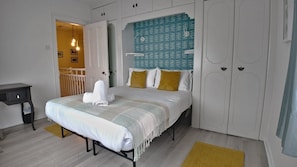 A bedroom with a bed, bedside tables, a wardrobe, and a door. - Thorn Cottage by Escape Ordinary (Ballycastle)