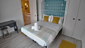 A bedroom with a bed, a desk, and a chair. There is a staircase leading to another room. - Thorn Cottage by Escape Ordinary (Ballycastle)