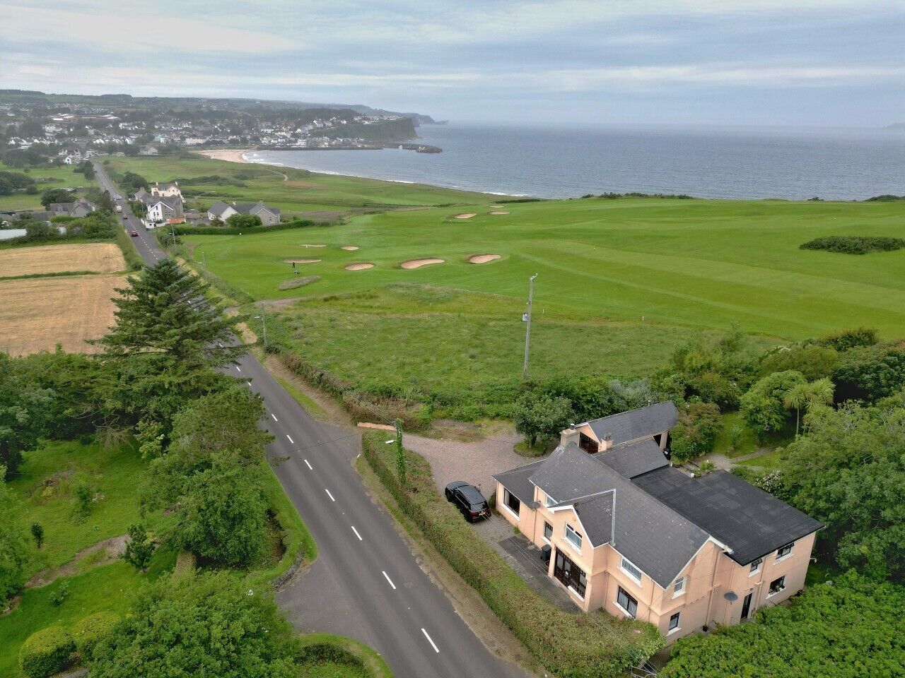 A coastal property with a road, a golf course, and a large building.