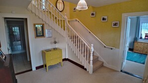 Eine Treppe mit weißen Balustraden und einer gelben Wand, eine kleine gelbe Kommode und ein gerahmtes Zertifikat an der Wand.